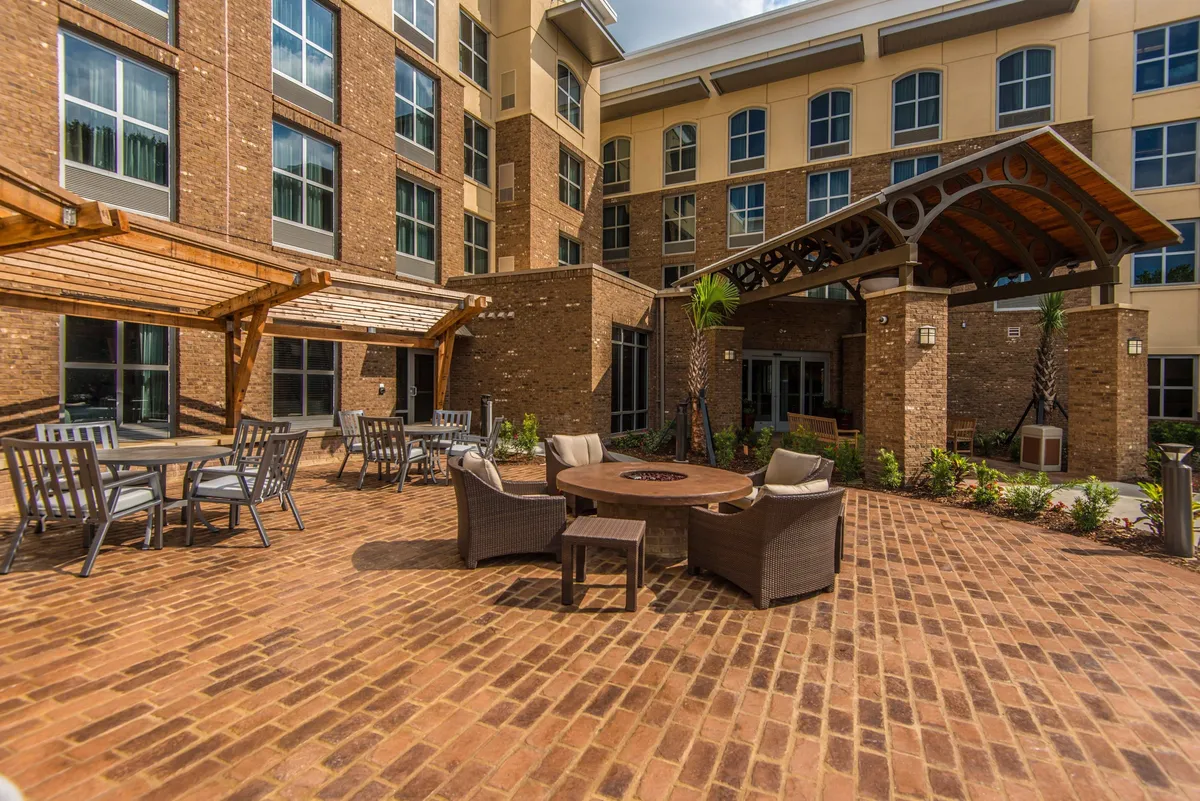 A spacious exterior area featuring a cozy fire pit, comfortable seating arrangements, and a stylish outdoor pergola. The setting is ideal for socializing or enjoying a peaceful evening outdoors, with an inviting ambiance that encourages both group gatherings and quiet moments for couples or solo travelers.