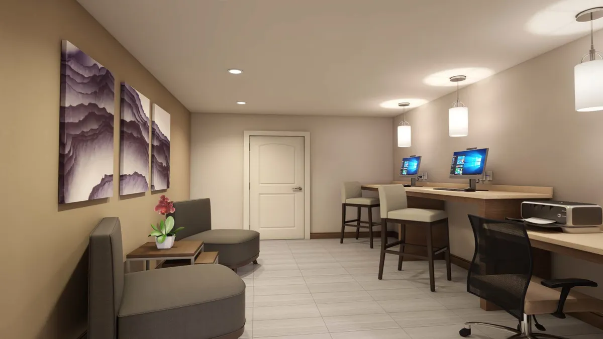 The image features a compact workspace area with computer stations, a seating area with a small table, and vibrant wall art. The overall mood is productive yet comfortable, echoing the versatility of the studio environment. This setup exemplifies a well-organized workspace ideal for business or creative pursuits as mentioned in the section content.