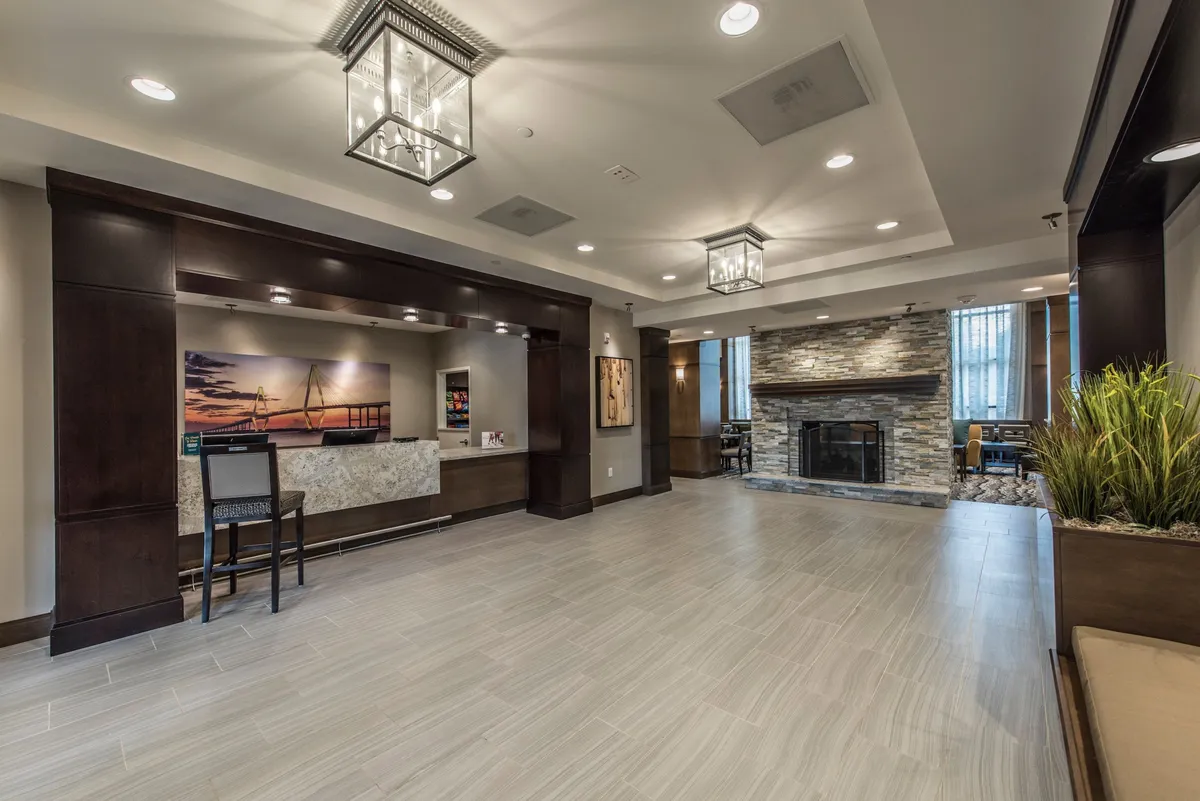 The inviting hotel reception area, featuring a sleek reception desk, cozy fireplace, local artwork, and a comfortable seating area. The ambiance is both welcoming and professional, ideal for guests arriving to check in or seeking assistance from guest services.